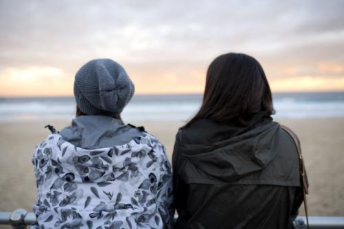 Two women looking out at the beach at sunset - Australian Stock Image