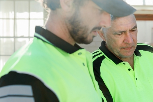 Two workers discussing  at a construction site - Australian Stock Image