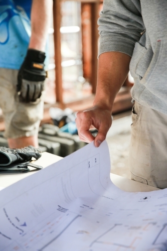 Two workers inspecting plans on a building site - Australian Stock Image