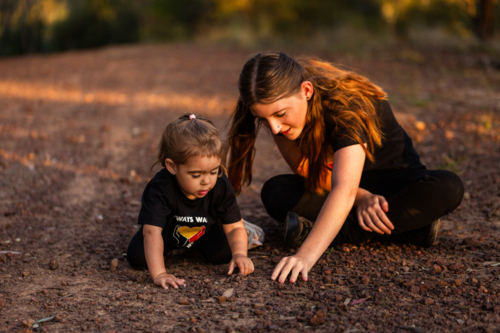 Two year old Australian toddler playing outside in nature with big sister - Australian Stock Image