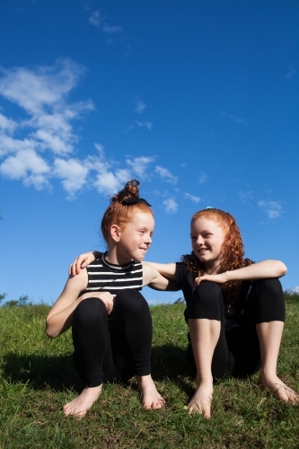 Two young girls sitting outside together - Australian Stock Image