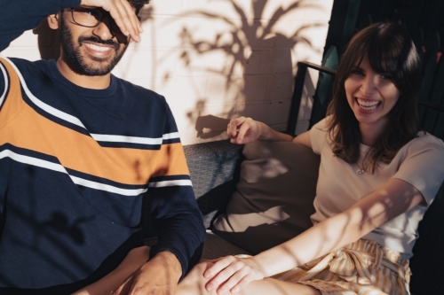 UGC style, couple sitting outside in the sun on their house veranda - Australian Stock Image