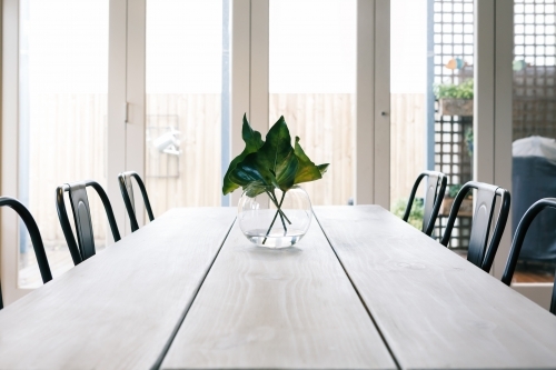 Uncluttered light bright contemporary dining room table with glass doors background - Australian Stock Image