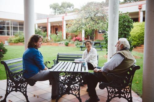 University teachers having a discussion at a bench in the garden - Australian Stock Image