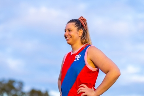 upper body of one young woman footballer with hands on hips against sky - Australian Stock Image