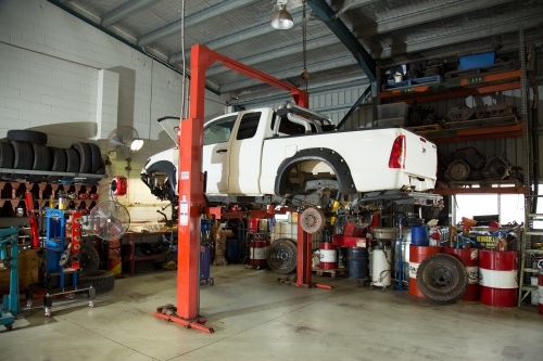 Ute lifted in hoist for repairs in a mechanic workshop - Australian Stock Image