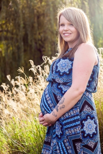 Vertical portrait of happy pregnant mother outside - Australian Stock Image