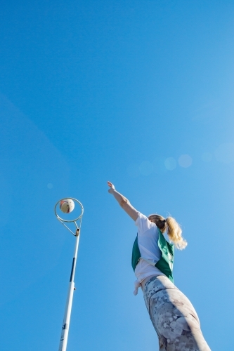 vertical shot of young woman throwing net ball in mid air on a sunny day - Australian Stock Image
