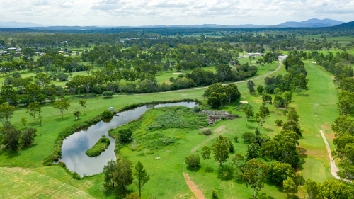 Vibrant green summer landscape showing a golf course and hills in the distance - Australian Stock Image