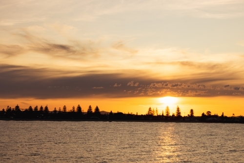 Vibrant orange sunset over Stockton NSW with view across the water - Australian Stock Image