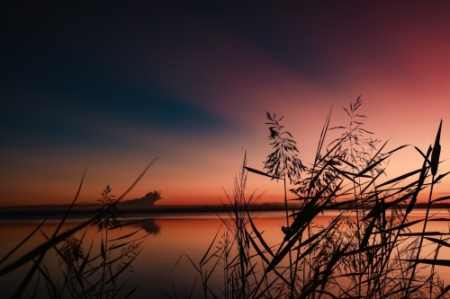 Vibrant sunset sky over Tuggerah Lake from Canton Beach on the Central Coast in Toukley, NSW - Australian Stock Image