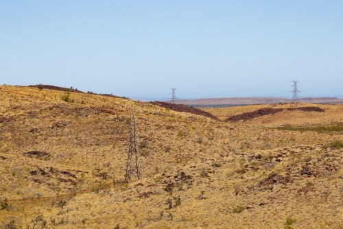 view across the barren pilbara landscape featuring high-tensile power lines - Australian Stock Image