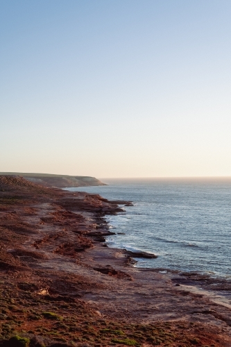 View along coastal rocky cliffs at sunset - Australian Stock Image