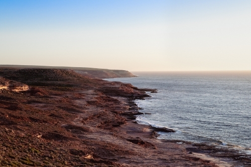 View along coastal rocky cliffs at sunset - Australian Stock Image