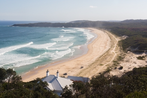 View from Sugar loaf point over lighthouse beach where people are four wheel driving - Australian Stock Image