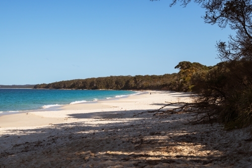 View of long white sandy beach with person in the distance - Australian Stock Image