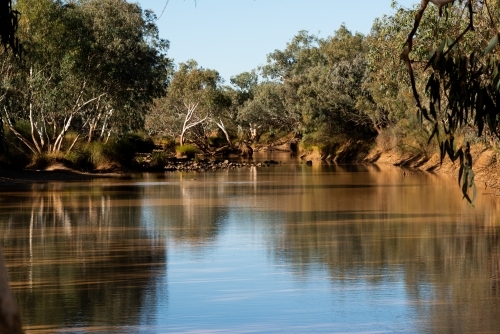 View of outback river with trees and long shadows - Australian Stock Image