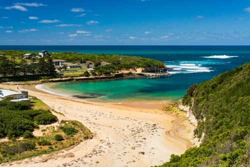 View of pretty scenic cove with green, blue waters, green headlands and blue sky - Australian Stock Image