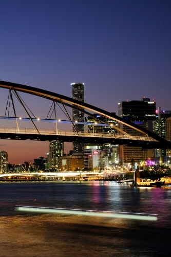 View of the Brisbane River at dusk with the Goodwill Bridge and lights from a passing ferry - Australian Stock Image