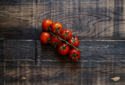 Vine ripened tomatoes on black timber background - Australian Stock Image