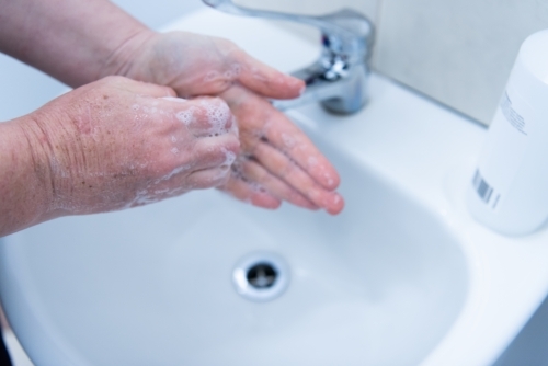 Washing hands with soap and water at basin - Australian Stock Image