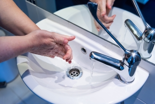 Washing hands with soap and water at basin - Australian Stock Image