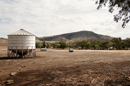 Water tank and feed bins in a dry paddock - Australian Stock Image