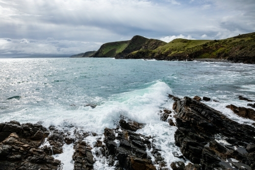 Waves coming in on rocks under a winter sky - Australian Stock Image