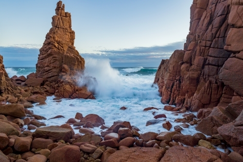 Waves crashing on a rocks along a coastline covered with large boulders and rock formations - Australian Stock Image