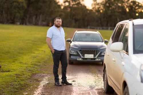 well dressed country bloke standing near car on rural gravel track - Australian Stock Image