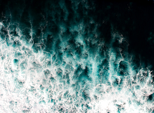 White wash and aqua patterns illuminate a dark ocean - Australian Stock Image