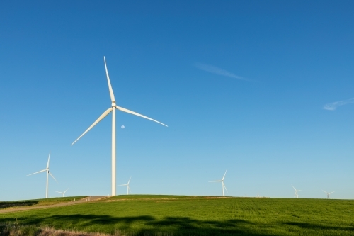 wind turbines against blue sky and green farmland - Australian Stock Image