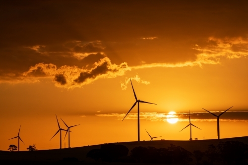 wind turbines silhouetted against setting sun - Australian Stock Image