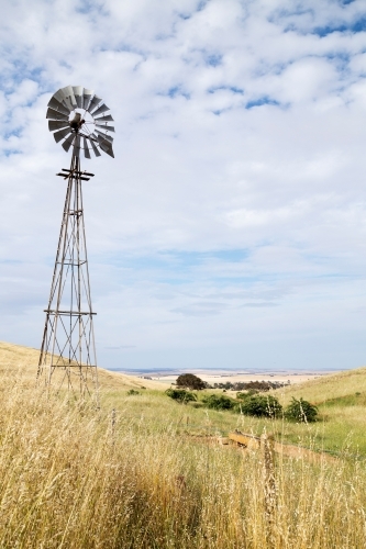 Windmill on a hillside against a cloudy sky - Australian Stock Image