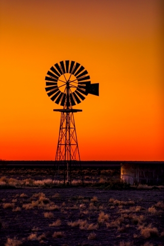 Windmill silhouette against an orange Sunset - Australian Stock Image