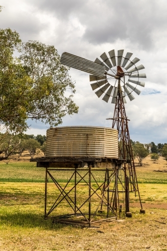 Windpump (windmill) and water tank on a dry farmland property - Australian Stock Image