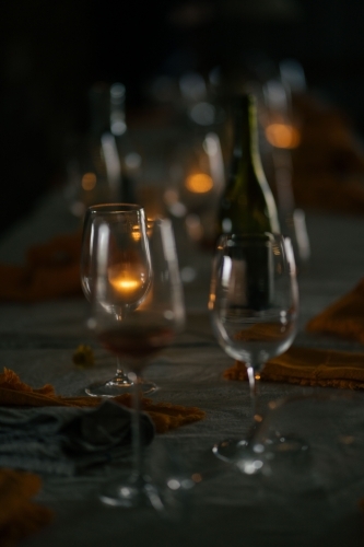 Wine glasses and a bottle of wine set on the table in a dimly lit scene
