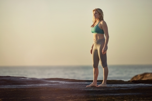 Woman doing yoga by the ocean - Australian Stock Image