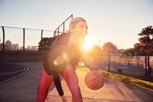 Woman dribbling basketball in the sun - Australian Stock Image