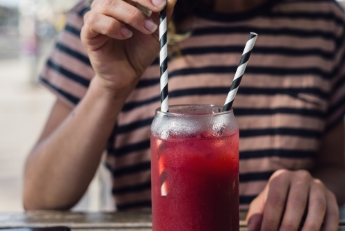 woman drinking fruit drink in a cafe - Australian Stock Image