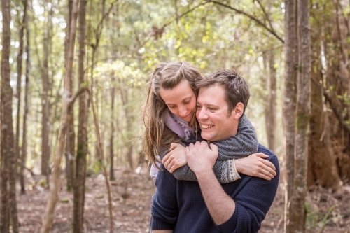 Woman embracing man from behind around neck lovingly - Australian Stock Image