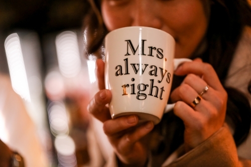 Woman enjoying coffee in Melbourne laneway with'Mrs Always Right' mug - Australian Stock Image