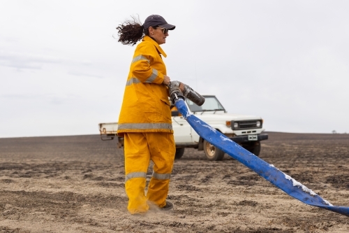 Woman firefighter holding hose at fire scene - Australian Stock Image