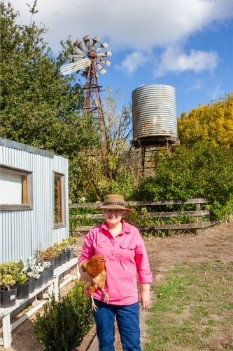 Woman holding a chicken in the farm - Australian Stock Image