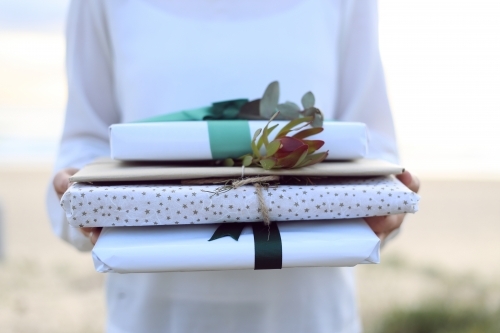 Woman holding presents at beach - Australian Stock Image