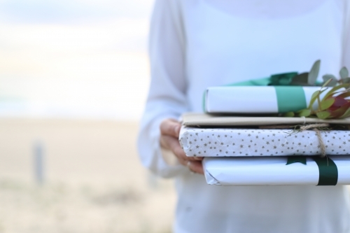 Woman holding presents with beach in background - Australian Stock Image