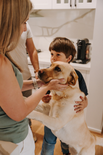 Woman holding the face of her pet dog with family - Australian Stock Image