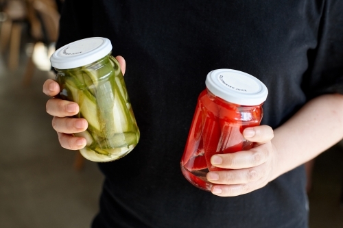 Woman holding two jars of homemade pickles