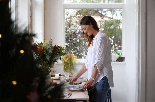 Woman in dining room setting Christmas table - Australian Stock Image