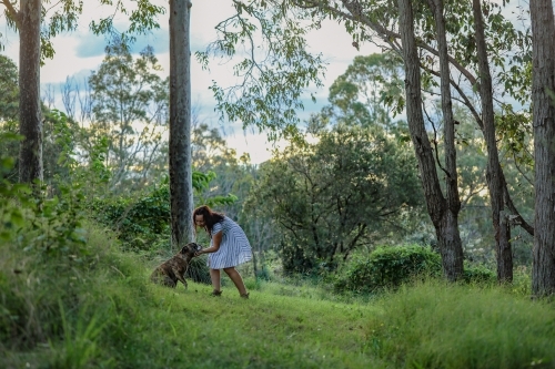 Woman in forest setting showing affection to pet dog - Australian Stock Image